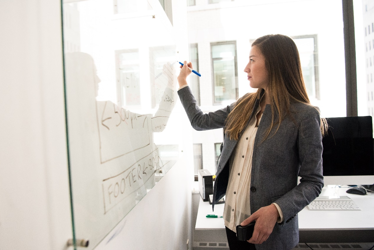 A woman writing on a board with a marker
