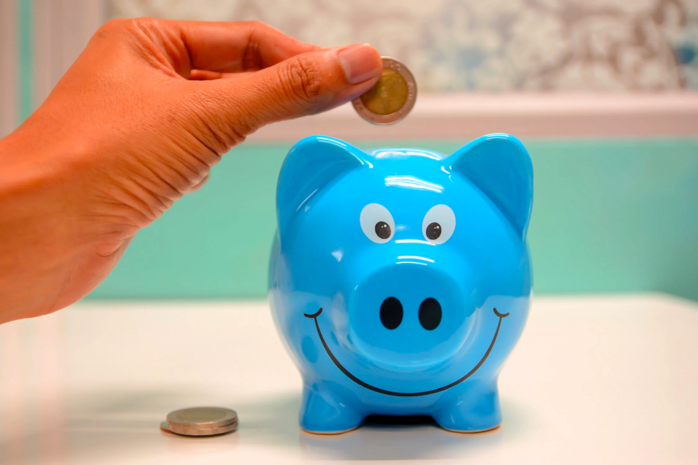 A person inserts coins into a piggy bank to save